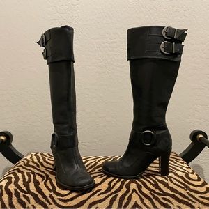 Knee high black boots with buckle details.